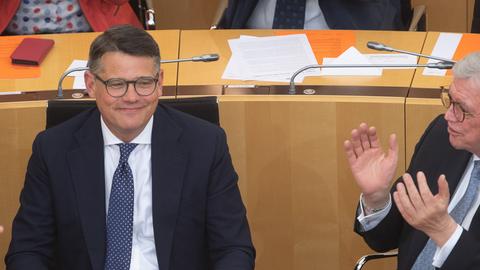 Volker Bouffier beklatscht Boris Rhein. Sie sitzen nebeneinander in den Reihen des Landtags.