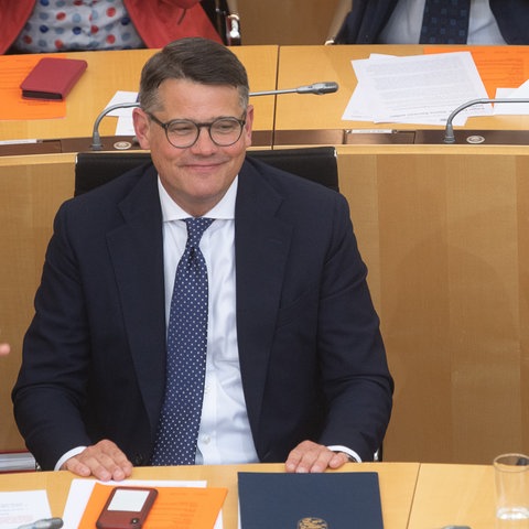 Volker Bouffier beklatscht Boris Rhein. Sie sitzen nebeneinander in den Reihen des Landtags.
