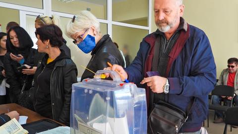 Ein Mann gibt einen Wahlzettel ab beim Scheinreferendum in einem russisch besetzten Gebiet in der Ukraine