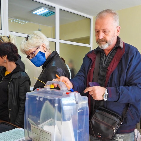 Ein Mann gibt einen Wahlzettel ab beim Scheinreferendum in einem russisch besetzten Gebiet in der Ukraine