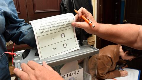 Eine Frau wirft einen Wahlzettel in eine Wahlurne.