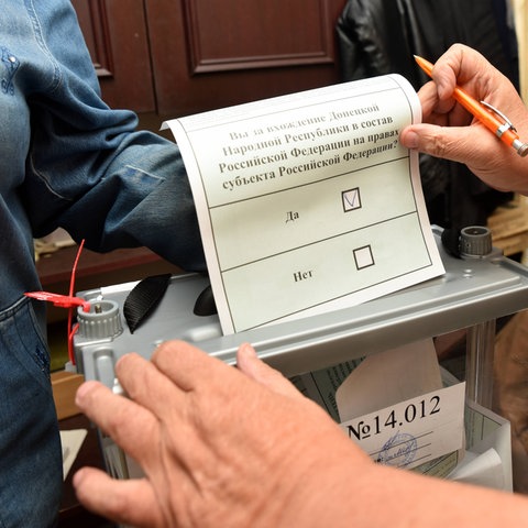 Eine Frau wirft einen Wahlzettel in eine Wahlurne.