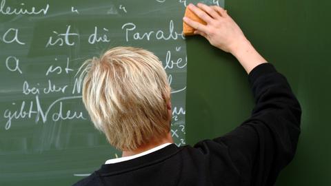 Ein Lehrer wischt eine Schultafel