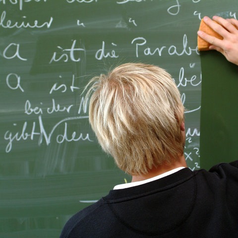 Ein Lehrer wischt eine Schultafel