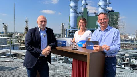 Rene Rock (FDP) steht mit einer Moderatorin und einem Moderator beim Sommerinterview auf einem Dach in Frankfurt