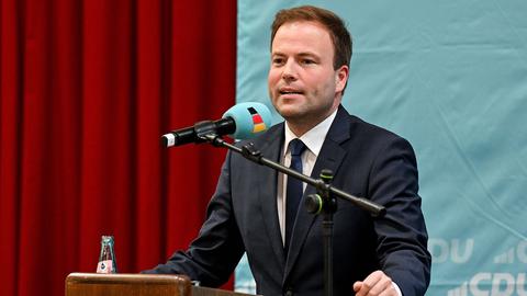 Sven Simon steht auf einer Bühne an einem Rednerpult, hinter ihm hängt ein Banner mit der Aufschrift CDU.