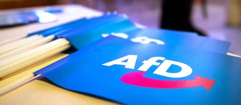 Fähnchen mit dem Logo der AfD liegen auf einem Tisch.
