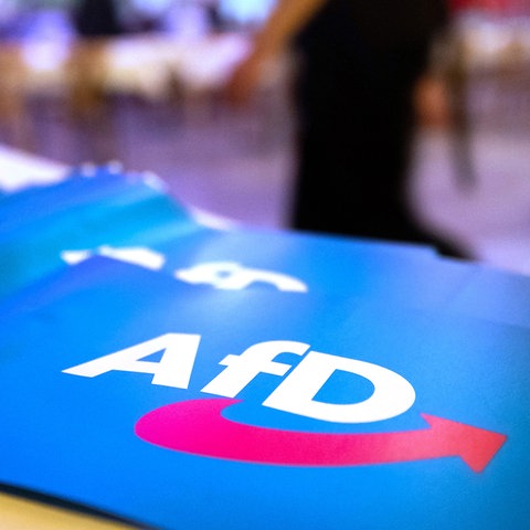 Fähnchen mit dem Logo der AfD liegen auf einem Tisch.