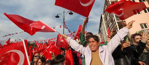 Menschen bei einer Wahlveranstaltung in der Türkei schwenken türkische Flaggen in ihren Händen