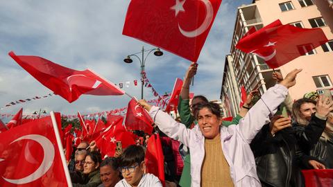 Menschen bei einer Wahlveranstaltung in der Türkei schwenken türkische Flaggen in ihren Händen