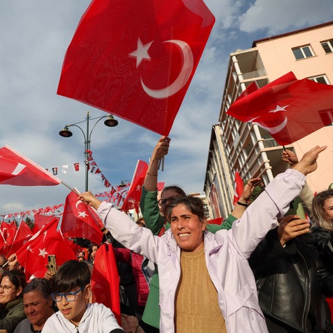 Menschen bei einer Wahlveranstaltung in der Türkei schwenken türkische Flaggen in ihren Händen