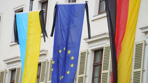 Die Fahnen der Ukraine, der Europäischen Union und von Deutschland hängen jeweils mit Trauerflor vor einem Gebäude des hessischen Landtags.
