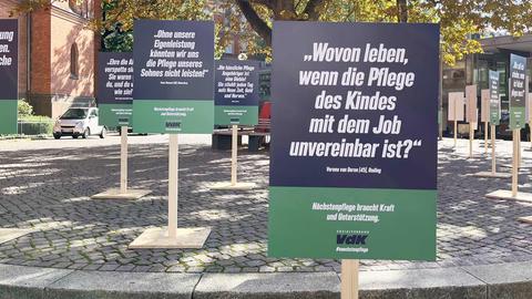 Schilder mit Statements auf selbste stehenden Schildern von Pflegenden (z.B. "Wovon leben, wenn die Pflege des Kindes mit dem Job unvereinbar ist") auf einem Platz