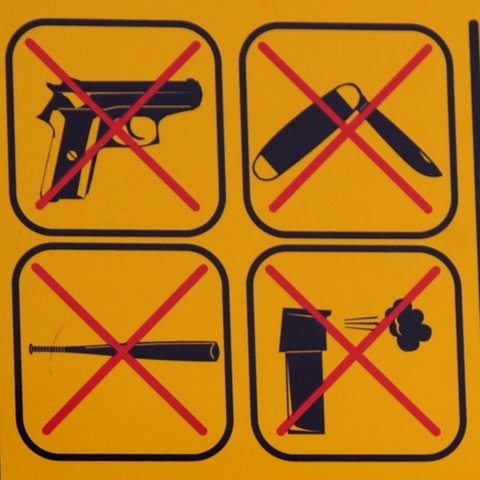 Symbolbild: Ein Schild "Waffen verboten" ist an einem Mast befestigt. 