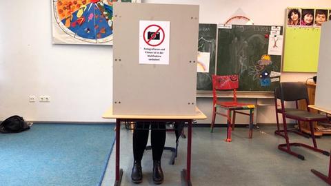 Eine Frau sitzt in einer Wahlkabine