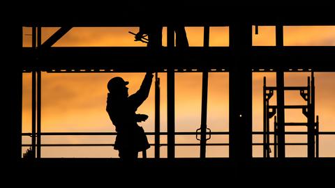 Bauarbeiter errichten bei Sonnenaufgang ein Gebäude. 