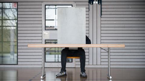 Ein Mann gibt in einem Wahllokal seine Stimme ab.