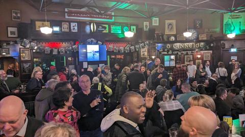 Menschen stehen in einem Irish Pub.