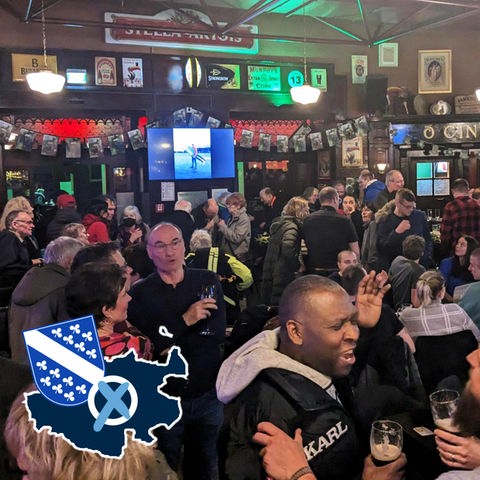 Menschen stehen in einem Irish Pub und feiern.