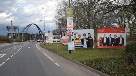 An einer Straße vor der Steinheimer Mainbrücke hängen Wahlplakete verschiedener Parteien.