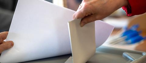 Eine Frau wirft ihren Stimmzettel in eine Wahlurne. 