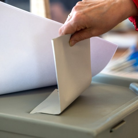 Eine Frau wirft ihren Stimmzettel in eine Wahlurne. 