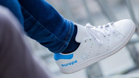 Ein weißer Turnschuh hat auf der Außenseite das Wort "europe" in hellblauer Schrift eingeprägt
