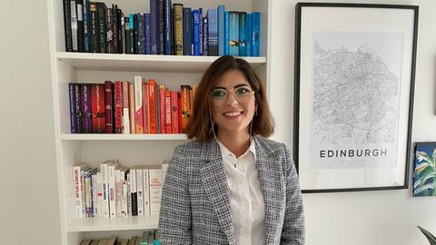 Reyhan Karadeniz steht vor einem Bücherregal