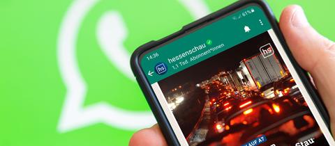 Vor einem grünen Hintergund mit einem WhatsApp-Logo ein Smartphone mit hessenschau-WhatsApp-Chat auf dem Bildschirm.