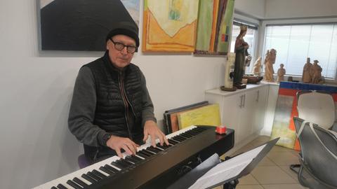 Komponist Siegfried Fietz Greifenstein sitzt an seinem Klavier in seinem Atelier