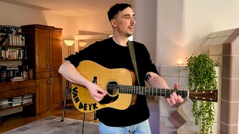 Mann mit Gitarre in einem Wohnzimmer