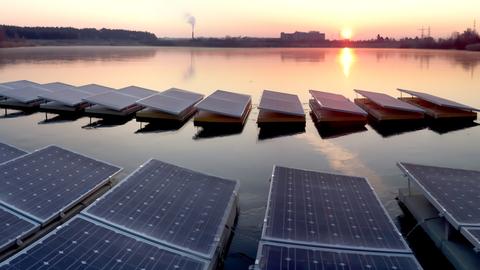 Sonnenuntergang am Baggersee in Babenhausen. Auf dem Wasser schwimmen in zwei Reihen einige Solaranlagen-Module.