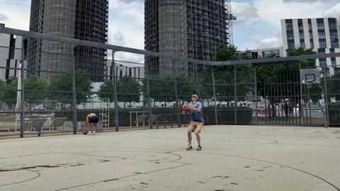 Das Bild zeigt einen Basketballer, der einen Ball in den Korb wirft.