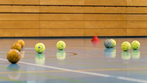 Handbälle liegen auf dem Boden einer Turnhalle.