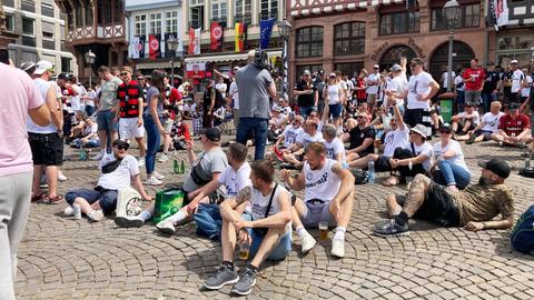 Viele Eintracht-Fans sitzen auf einem städtischen Platz - der Römerberg in Frankfurt. Im Hintergrund Fachwerkfassaden.
