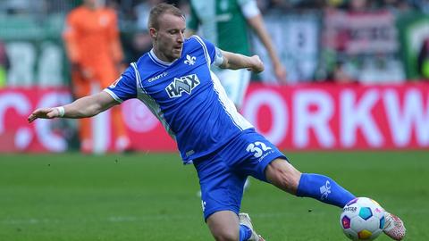 Fabian Holland (in blauem Darmstadt-Trikot) wirft sich in einen Ball. 