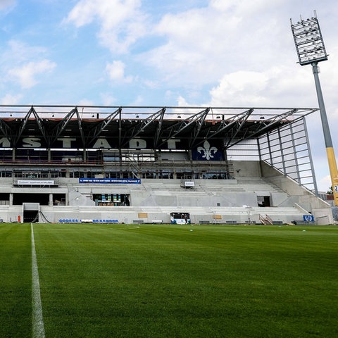 Leere Tribüne eines Fußballplatzes mit zwei großen Scheinwerfern rechts und links.