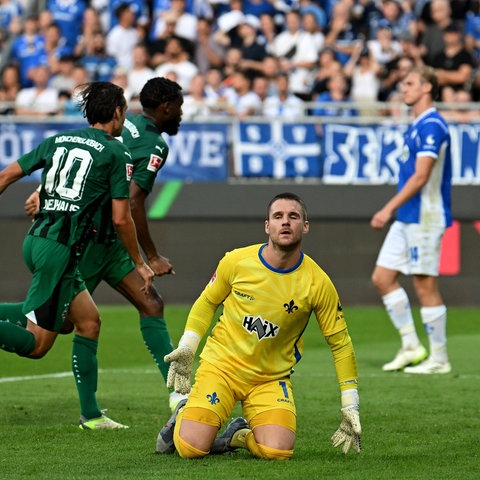 Marcel Schuhen auf dem Boden, hinter ihm jubelt Mönchengladbach.