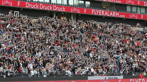 Die Fan-Kurve im Spiel der Eintracht Frauen gegen Wolfsburg. Die Fans halten weiß-schwarz-gestreifte Schals hoch.