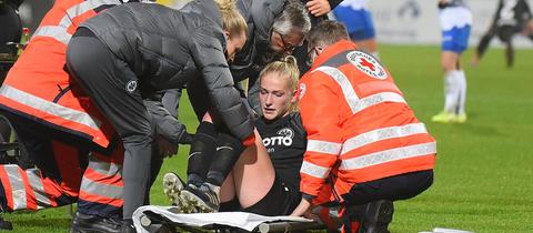 Camilla Küver von Eintracht Frankfurt wird auf dem Platz behandelt.