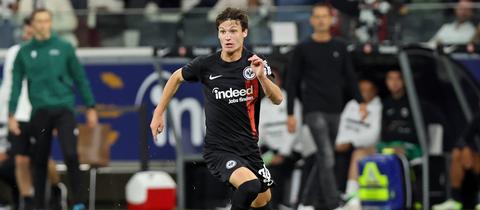 Paxten Aaronson im Trikot von Eintracht Frankfurt am Ball.