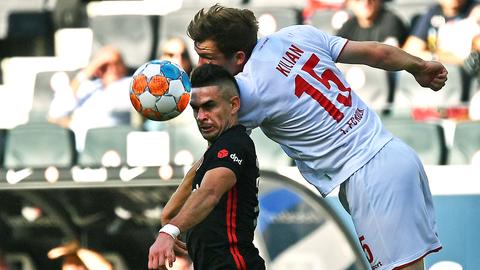 Rafael Borre Luca Kilian ringen springend um einen Ball auf dem Fußballfeld.