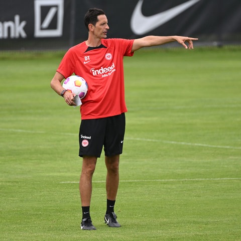 Toppmöller steht in einem roten Trikot im Trainingslager in Windischgarsten auf dem Rasen. In seiner Hand hält er einen Fußball.