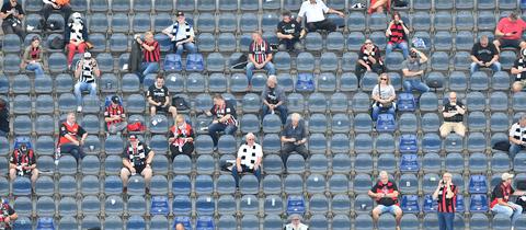 Einige Fans schauen das Spiel der Eintracht gegen Bielefeld im Frankfurter Stadion.