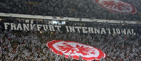 Ränge eines Stadions mit sehr vielen Fans und zwei Bannern mit dem Eintracht-Logo.