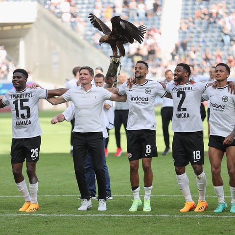 Die Spieler von Eintracht Frankfurt und Trainer Glasner stehen Arm in Arm vor der Kurve.