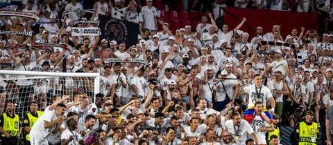 Die Mannschaft posiert mit dem Pokal vor den Fans. 