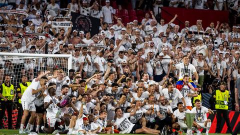 Die Mannschaft posiert mit dem Pokal vor den Fans. 