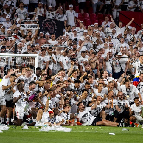 Die Mannschaft posiert mit dem Pokal vor den Fans. 