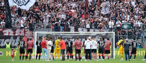 Spieler der Eintracht vor der Fankurve